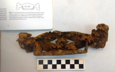 A rusty coffin handle showing two hearts lying on their sides and facing each other.